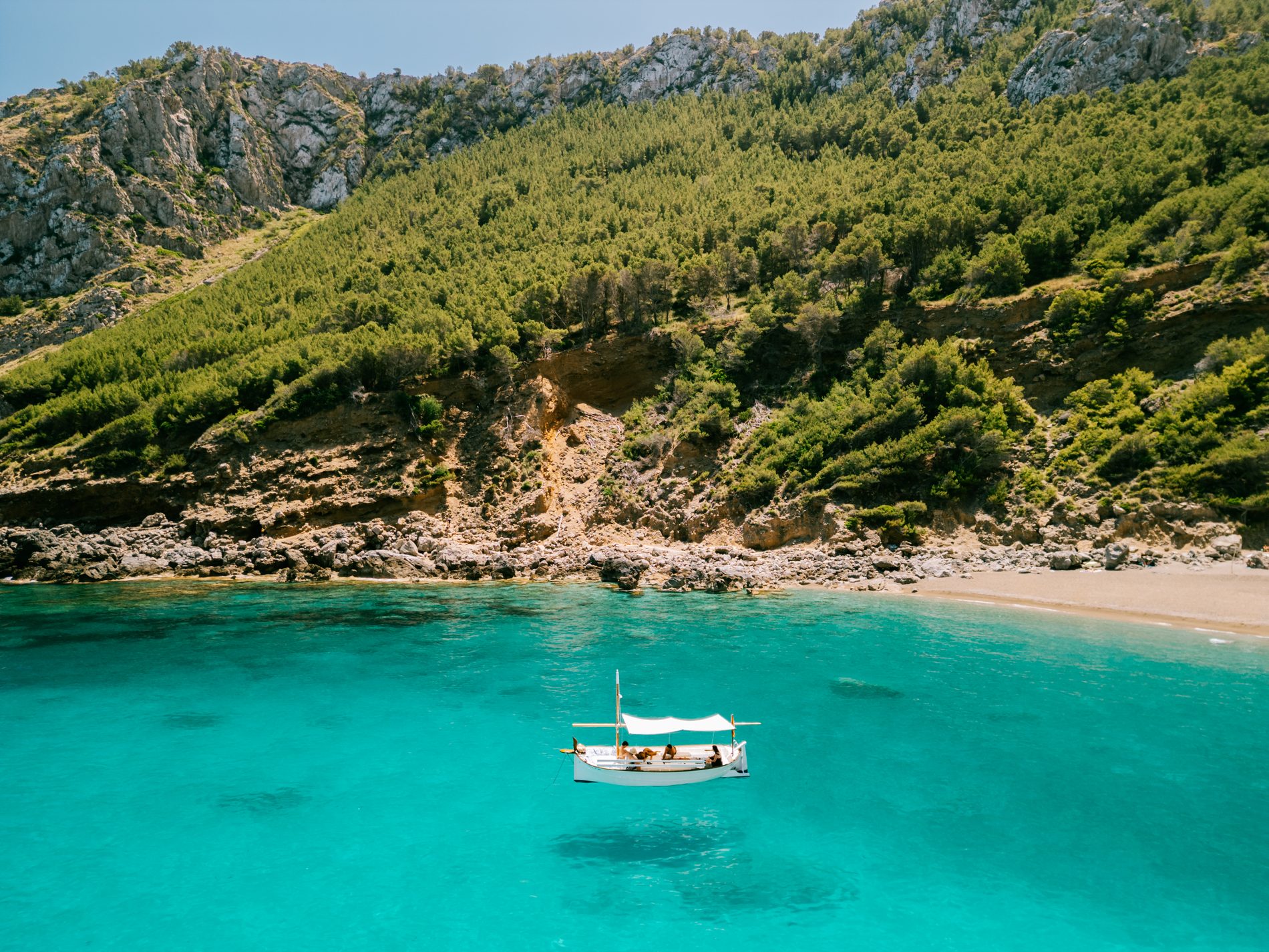 El llaüt Na Rumba fondeado en una cala turquesa del norte de Mallorca, boat charter y excursiones